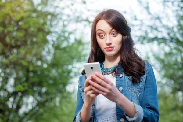 Verblüffte junge Frau mit Smartphone — Stockfoto