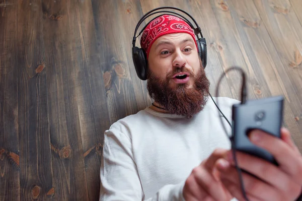 Uomo barbuto in cuffia con smartphone — Foto Stock