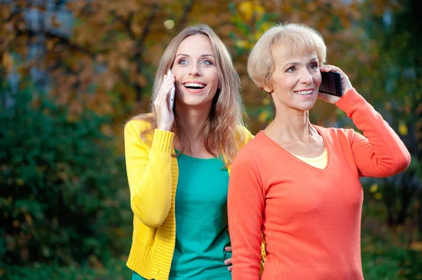 Mother and adult daughter talking on phones