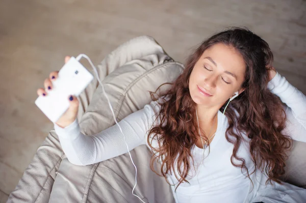 Jonge vrouw met oortelefoons en smartphone — Stockfoto