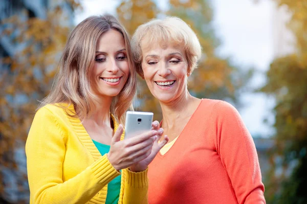 Mother with her daughter using phone — Stock Photo, Image