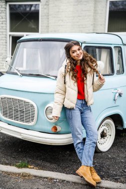 Genç güzel kız turkuaz arabanın yanında duruyor.