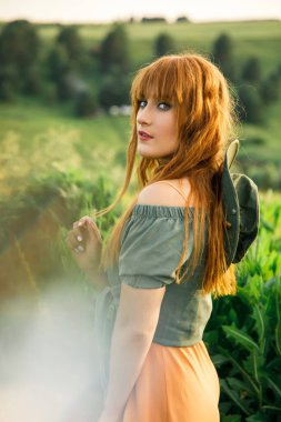 Pembe elbiseli, beyaz tişörtlü, beyaz tişörtlü, mavi şortlu genç ve güzel bir çift gün batımında çimlerin üzerinde eğleniyor.