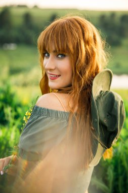 Pembe elbiseli, beyaz tişörtlü, beyaz tişörtlü, mavi şortlu genç ve güzel bir çift gün batımında çimlerin üzerinde eğleniyor.