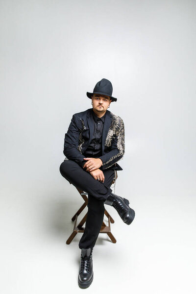 портрет жестокого человека в шляпе и черной одежде на белом фоне
