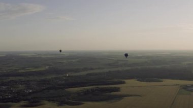 Gün batımında uçan balonlarla tarlaların üzerini görmek