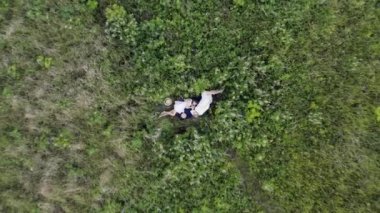 Elbise giymiş iki genç kız gün batımında lupinlerle çimlerin üzerinde uzanıyorlar.