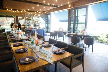 Şölen masası tabaklar, çatal bıçaklar, bardaklar, mumlar ve çiçek düzenlemeleri ile süslenir.