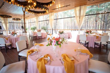 Şölen masası tabaklar, çatal bıçaklar, bardaklar, mumlar ve çiçek düzenlemeleri ile süslenir.