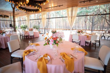 Şölen masası tabaklar, çatal bıçaklar, bardaklar, mumlar ve çiçek düzenlemeleri ile süslenir.