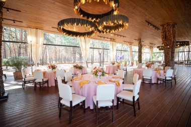 Şölen masası tabaklar, çatal bıçaklar, bardaklar, mumlar ve çiçek düzenlemeleri ile süslenir.