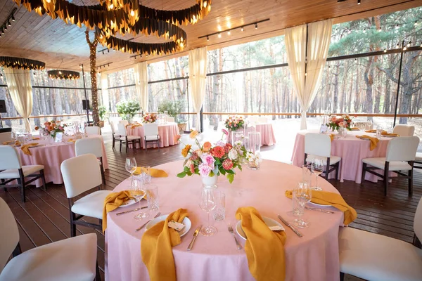 Şölen masası tabaklar, çatal bıçaklar, bardaklar, mumlar ve çiçek düzenlemeleri ile süslenir.