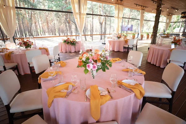 Şölen masası tabaklar, çatal bıçaklar, bardaklar, mumlar ve çiçek düzenlemeleri ile süslenir.