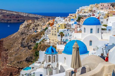 Yunanistan 'ın Santorini adasındaki Oia köyünün kubbeleri ve kiliseleriyle tipik beyaz ve mavi mimari.