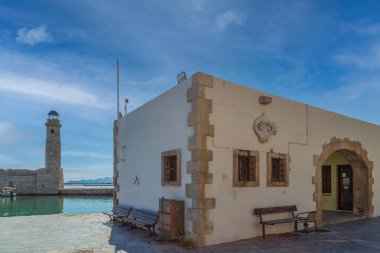 RETHYMNO, CRETE, GREECE-JUNE 19, 2021: Venedikliler tarafından 13. yüzyılda inşa edilen eski liman, Mısırlı deniz feneri ve fresk Marina gezinti güvertesinde iki yunusbalığıyla birlikte inşa edildi, şehrin tarihi sembolü.