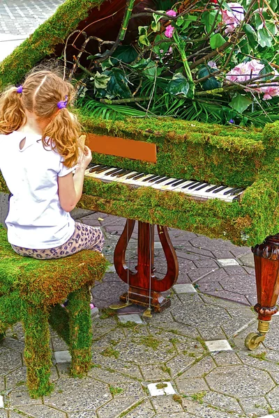 Kleines Mädchen singt an einem mit Blumen geschmückten Flügel 1 — Stockfoto