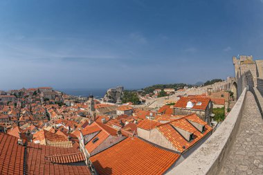 Hırvatistan 'ın Dubrovnik kenti, ortaçağ kale duvarlarının zirvesinden çatıları ve arka planında Fort Lovrijenac kalesiyle eski kasaba manzarası.