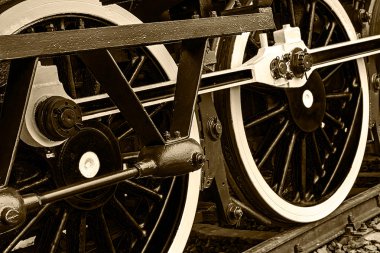 Sepia detail and close up of huge wheels at one old steam locomo clipart