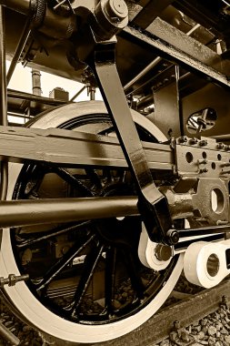 Sepia detail and close up of huge wheels at one old steam locomo clipart