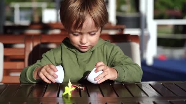 Мальчик распаковывает яйца с сюрпризом — стоковое видео