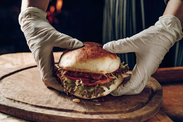 Eldivenli eller, tahta tepsiden bir hamburger al.