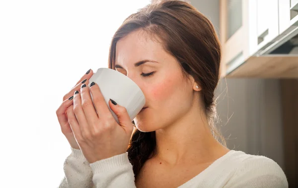 Žena s šálkem kávy nebo čaje, ráno v kuchyni — Stock fotografie