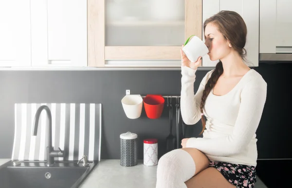 Kvinna med kopp kaffe eller te i köket — Stockfoto