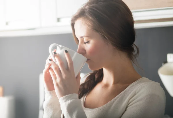 Kvinna med kopp kaffe eller te i köket — Stockfoto