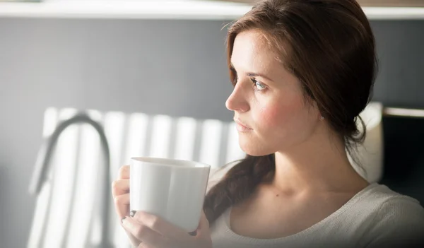 Mulher com xícara de café ou chá na cozinha — Fotografia de Stock