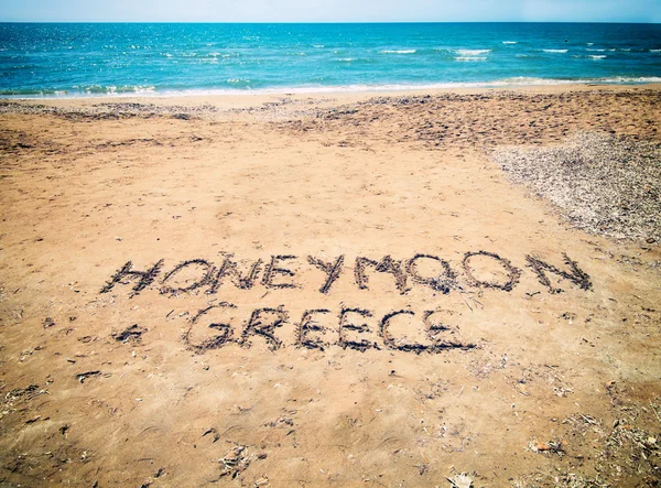 Luna di miele in Grecia scritta sulla spiaggia di sabbia vicino al mare — Foto Stock