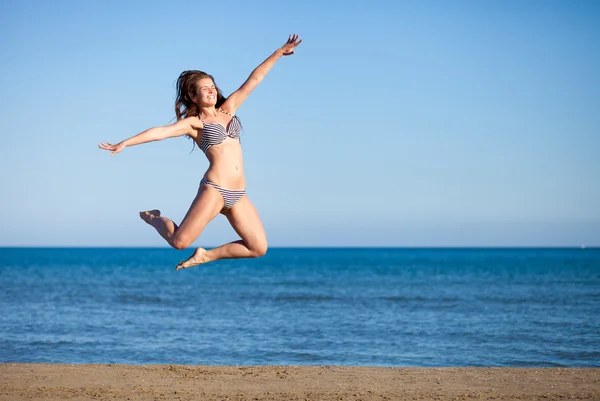 夏休みを楽しんでいるビーチでジャンプ女性 — ストック写真