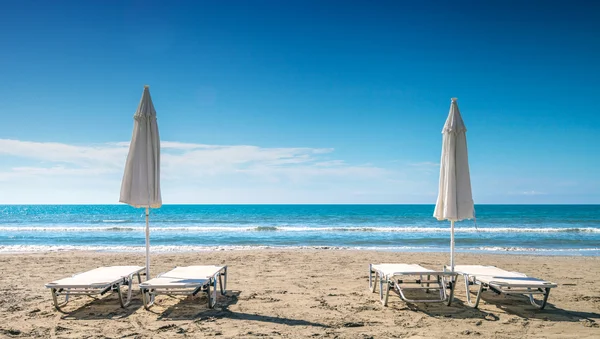 Kumlu plajda güneş şemsiyesi ile boş şezlong