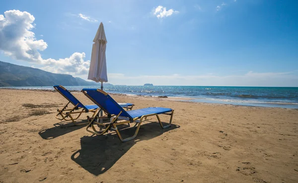 Empty lounge chairs with sun umbrella on sandy beach — Stock Photo, Image