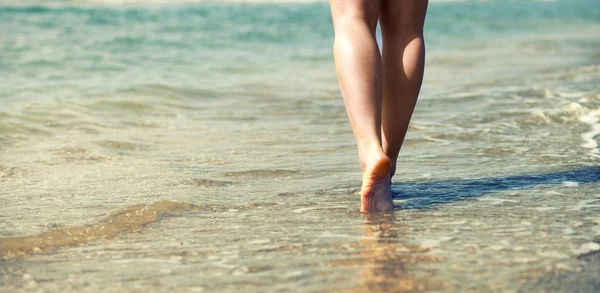 Mujer caminando en la playa de arena, pies en las olas del mar —  Fotos de Stock