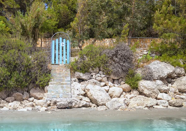 Blauwe deur naar het strandhuis in de buurt van turquoise zee — Stockfoto