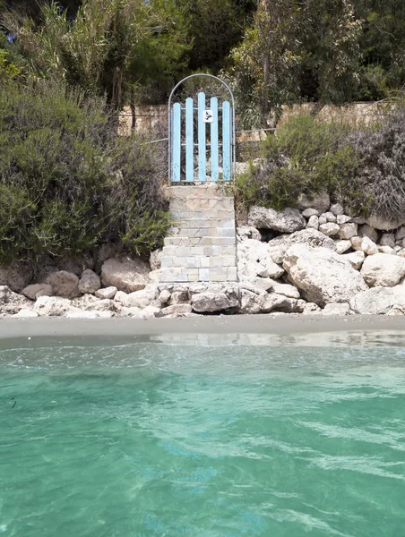 Blauwe deur naar het strandhuis in de buurt van turquoise zee — Stockfoto