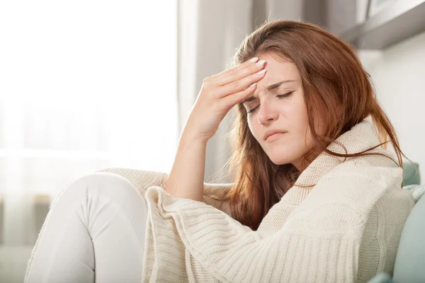 Jonge vrouw met hoofdpijn liggend op Bank thuis. casual stijl binnen schieten — Stockfoto