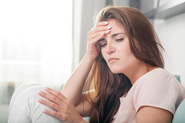 Mujer joven con dolor de cabeza tumbada en el sofá en casa. estilo casual rodaje interior —  Fotos de Stock