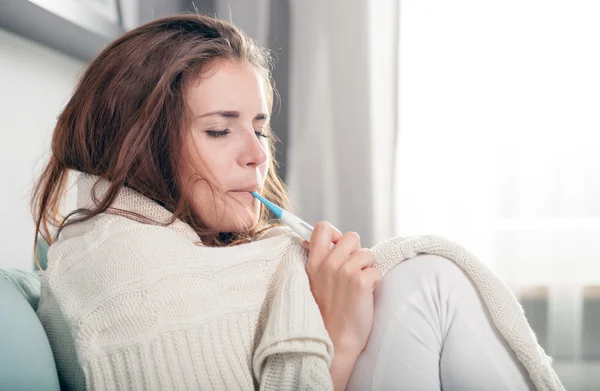 Young woman having flu lying on couch at home. Casual style indoor shoot — Stok fotoğraf