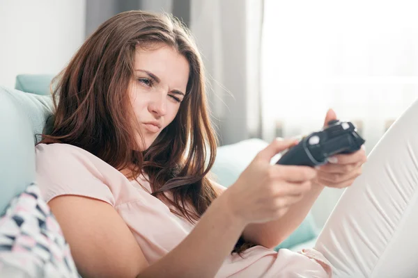 Jonge vrouw op de Bank thuis zitten en spelen van videospellen — Stockfoto