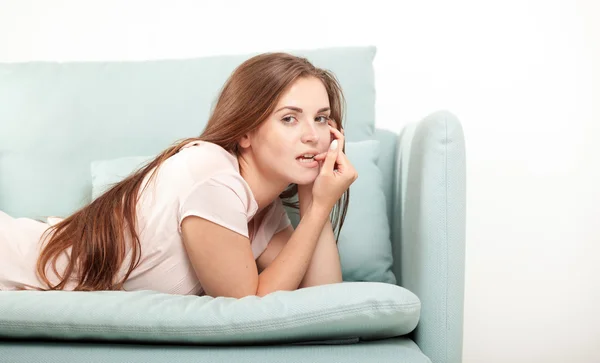 Jeune femme allongée sur le canapé à la maison regardant vers la caméra. Tournage de style domestique — Photo