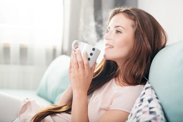 Jovem mulher sentada no sofá em casa e bebendo café. Casual estilo interior atirar — Fotografia de Stock