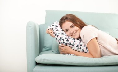 Young woman laughing and lying on couch at home. Domestic style shoot