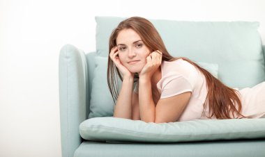 Gülümseyen genç kadın evde kanepede yatıyor. Yerli stil çekimi