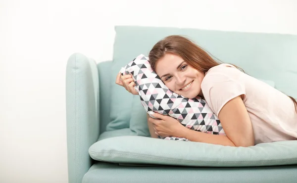 Jeune femme riant et allongée sur le canapé à la maison. Tournage de style domestique — Photo