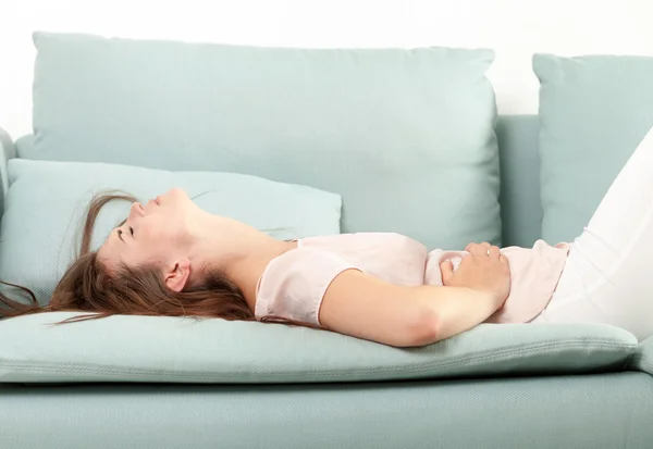 Giovane donna nel dolore sdraiata sul divano a casa. Scatto al coperto stile casual — Foto Stock