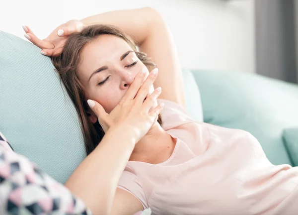 Jovem sonolenta deitada no sofá e relaxante em casa. Casual estilo interior atirar — Fotografia de Stock