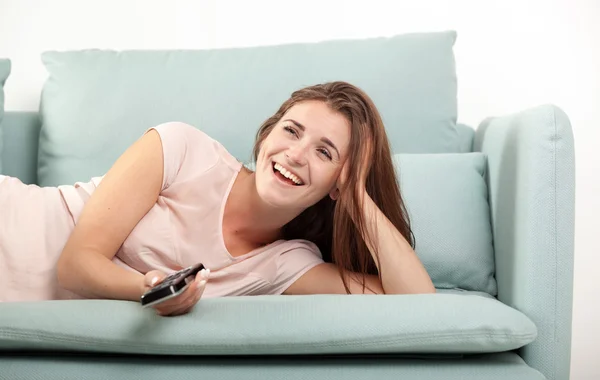 Lachende junge Frau auf dem heimischen Sofa und vor dem Fernseher. Casual Style Indoor Shooting — Stockfoto
