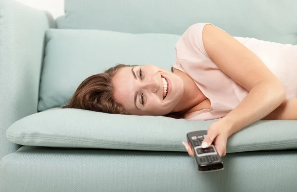 Lachende junge Frau auf dem heimischen Sofa und vor dem Fernseher. Casual Style Indoor Shooting — Stockfoto