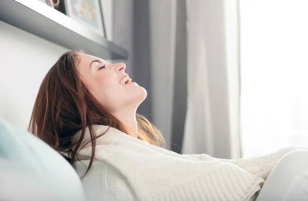 Gelukkig jonge vrouw liggend op Bank thuis en lachen. Casual stijl binnen schieten — Stockfoto